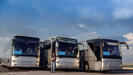 Three buses staying in the parking lot. Front view of the buses with blue sky and clouds.の写真素材