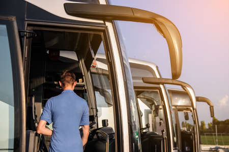 Driver staying in the front door of his bus. Happy driver meeting his passengers to his bus.の写真素材