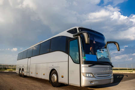 Bus staying in the parking lot under a blue sky with clouds. Lateral view of a busの写真素材