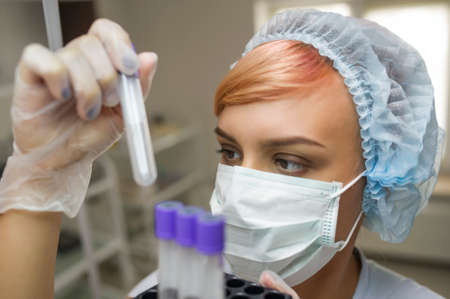 lateral view of a woman with mask looking at a tubeの写真素材