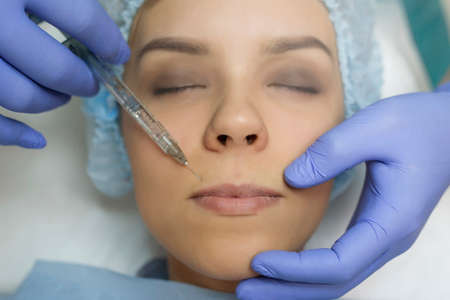 Top view of lips augmentation procedure on a young woman done by a cosmetologist doctor with Hyaluronic acid Injection.の写真素材