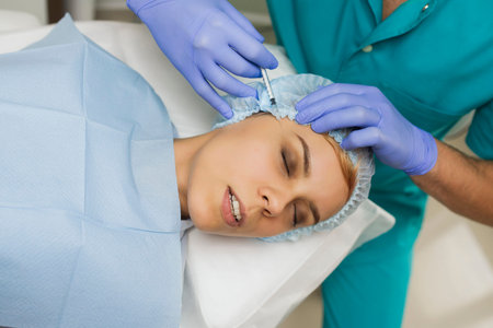 top view of eye augmentation procedure on a young woman done by a cosmetologist doctor with...