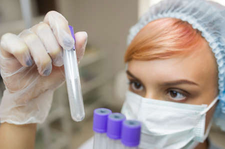 lateral view of a woman with mask looking at a tubeの写真素材