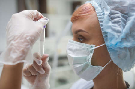 later view of a woman with mask looking at a tubeの写真素材