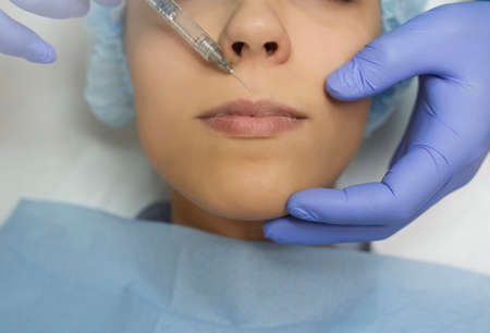 Top view of lips augmentation procedure on a young woman done by a cosmetologist doctor with Hyaluronic acid Injection.の写真素材
