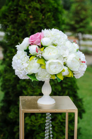 Wedding presidium table with pink tablecloth, floral arrangements: a bouquet of flower in a glass vase, candles in glass supportの写真素材