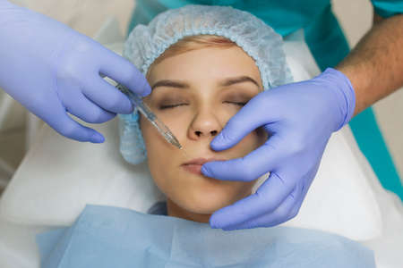 Top view of lips augmentation procedure on a young woman done by a cosmetologist doctor with Hyaluronic acid Injection.の写真素材