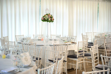 Lateral view of round wedding table with white tablecloth and all necessary supplies for dinner on...