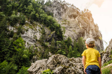 A 6-years blond boy near a rocky mountainの写真素材