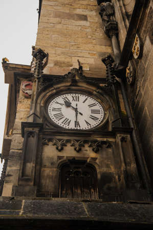 Closeup photo of a medieval clock on the wall of a very old brown historical buildingの写真素材