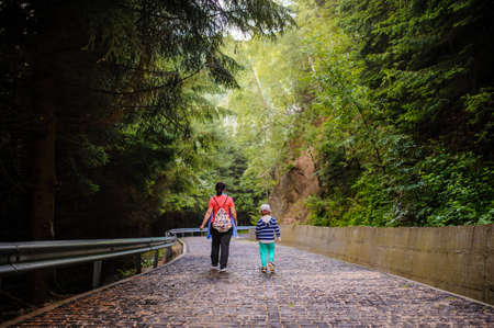 a boy and a girl walking on a stone path in a forestの写真素材