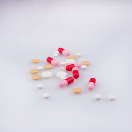white and yellow pills, red-pink capsules on a white backgroundの写真素材