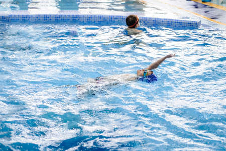 a 6-year boy swims backstroke in a swimming pool for kidsの写真素材