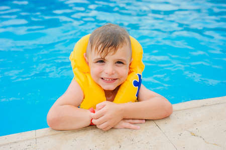 a 6-year blond boy in a life vest at the swimming pool of a hotel in Turkeyの写真素材