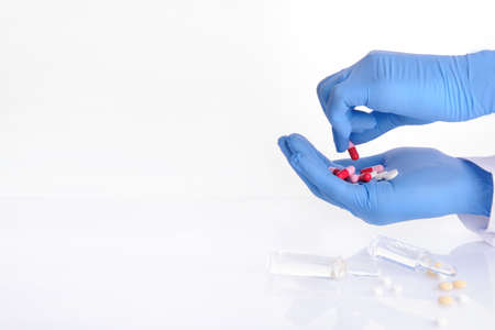 the hands of a doctor holding pills of different color; ampoules with medicineの写真素材