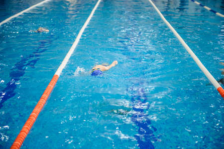 a 6-year boy swims backstroke in a swimming pool for competitionの写真素材