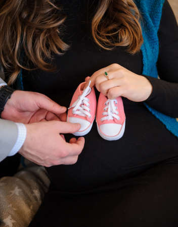 Future parents holding baby's pink boots in their handsの写真素材