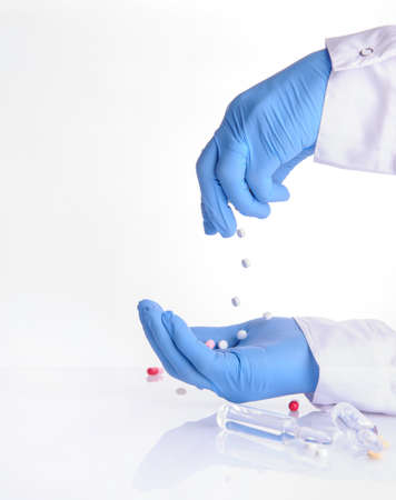 the hands of a doctor holding pills of different color; ampoules with medicineの写真素材