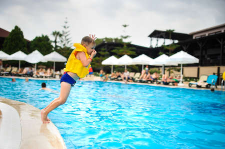 a 6-year blond boy in a life vest jumping in the swimming pool of a hotel in Turkeyの写真素材