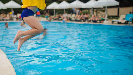 a 6-year blond boy in a life vest jumping in the swimming pool of a hotel in Turkeyの写真素材