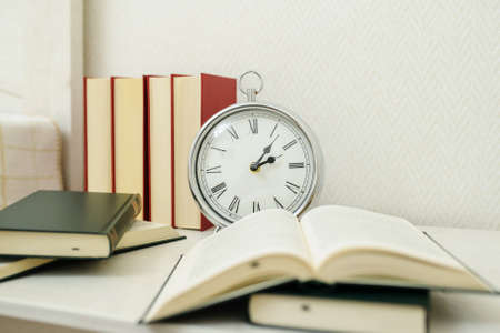 a silver vintage clock on the nighstand near booksの写真素材
