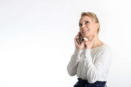 20-years blond girl in white blouse and blue skirt on white background talking on the cell phoneの写真素材