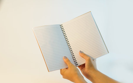 Female hands holding blank open notebook on a white background