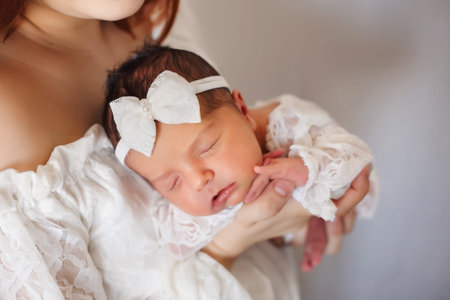 Proud mother with tiny newborn girl sleeping in her arms
