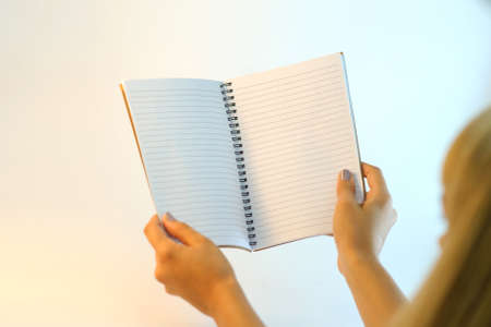 Female hands holding blank open notebook on a white backgroundの写真素材