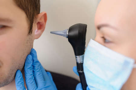 close up photo of a female otolaryngologist examining the ear of a male patientの素材 [FY310152356162]