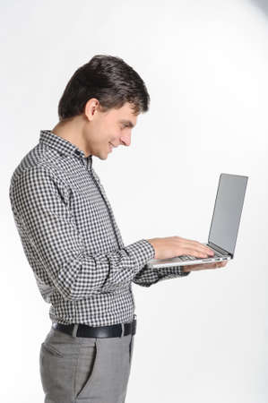 30-years brunet man in a grey outfit on a white background working at the laptopの写真素材