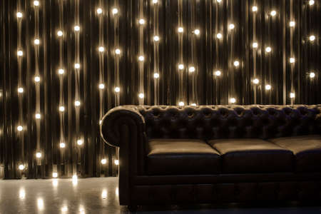 close up photo of a leather couch in a dark room on the background of bright lightsの写真素材