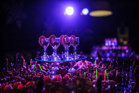 Buffet table with snacks, canapes; shrimp with sauce in glasses at a birthday party in blue lights