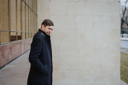 lateral view of a young man in a classic coat outdoorsの写真素材
