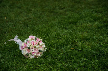 close up photo of a bridal bouquet from white and pink roses  and eustoma on the grassの写真素材