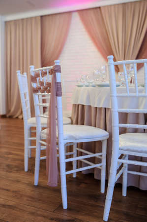 close up photo of white chairs decorated with brown textil in a banquet hall in white and brown colors decorated for the eventの写真素材
