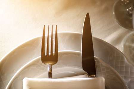 close up photo of knife and fork in a folded napkin on two plate