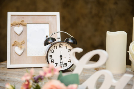 closeup photo of a wedding decor: a vintage wooden table with a flower arrangement, photo frame,...