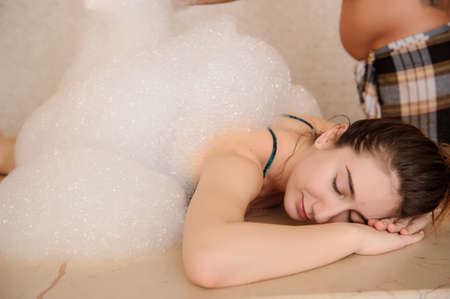 Young woman in white foam relaxing in a hamamの写真素材