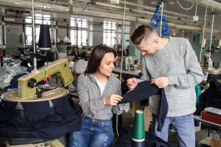 close up photo of a young man and a woman analyzing the work at the linking machine for knitting in textile industryの写真素材