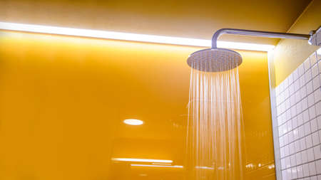 Close up shower in yellow bathroom with glossy surface. Copy space for you textの写真素材