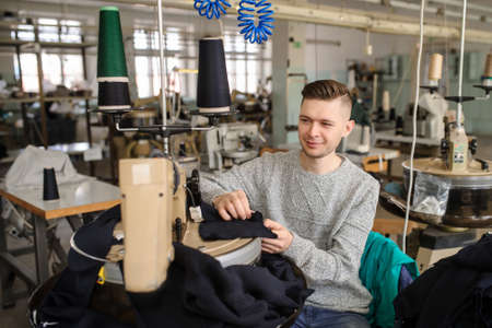 close up photo of a young man working with linking machine for knitting in textile industryの写真素材