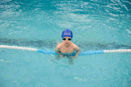 top view of a 7-year boy playing and swimming in the swimming poolの写真素材