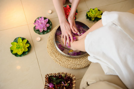 lateral view of a woman's foot washing procedure before spa treatment in a salon done by a masseuse;...