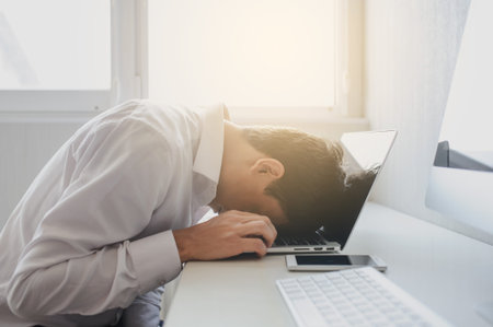 lateral view of a young man in white shirt with his head on the notebook and thinking about a task
