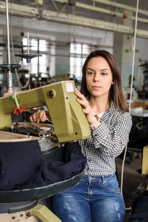 close up photo of a young woman working with linking machine for knitting in textile industryの写真素材