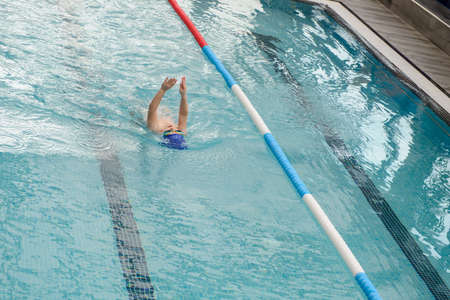 top view of a 7-year boy swimming backstroke in a swimming poolの写真素材