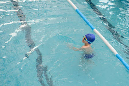 top view of a 7-year boy playing and swimming in the swimming poolの写真素材
