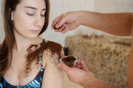 close up photo of a beautiful woman in spa salon having spa therapy with coffee done by a masseurの写真素材