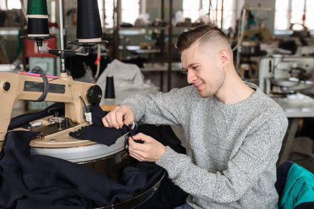 close up photo of a young man working with linking machine for knitting in textile industry